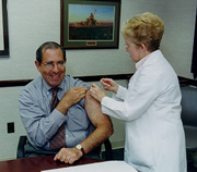 CC Director Dr. John Gallin rolls up his sleeve to receive his annual flu shot from Muriel Brenner, R.N., of OMS.