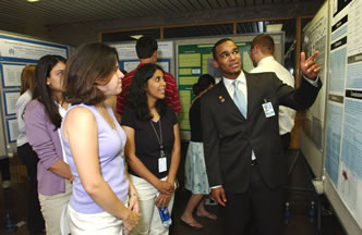 Student David Jones describes his research to fellow summer intern-students Jennifer Hicks and Kavita Poddar who also participated in the poster day event at the Clinical Center.