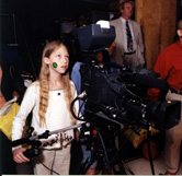 a young girl standing behind a video camera