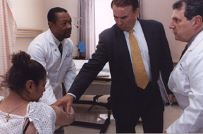 photo of Secretary Thompson touching the arm of Rosa Ramirez, a patient at the Clinical Center