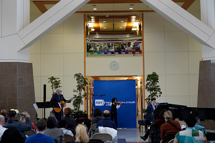 Caesar Santos, Dr. Francis Collins, and Robert Masi performing in the CC Atrium