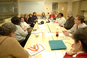 A photo of the weekly pain and palliative care meeting showing a group of CC staff members around a conference table.
