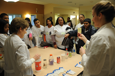 Clinical research dietitians show the students the sugar content of a variety of drinks.