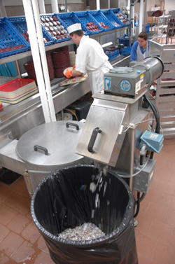 Food service workers feed items from patient trays into the dish room pulper.