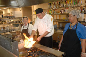 CC chef demonstrates technique for two staff members