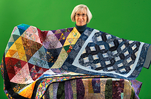 Jane Campos holding several quilts.