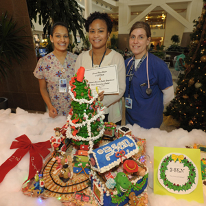 three women stand behind an edible Toy Story creation with a Christmas tree and train