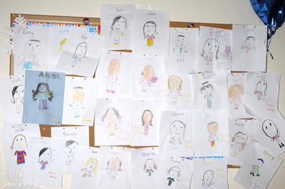 crayon and construction paper drawings of staff members on a bulletin board
