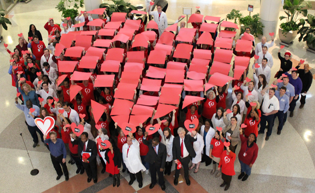 A large croud of people holding up a geometric heart to celebrate American Heart Month