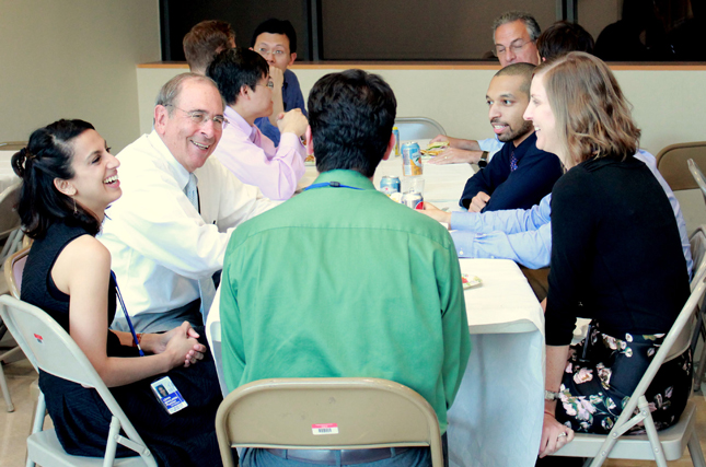 Dr. John I. Gallin (second from left), talking to fellows at a table