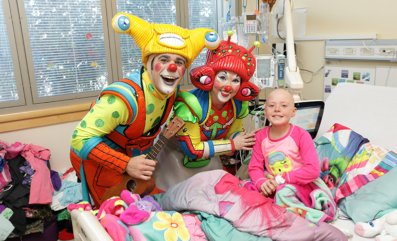 A bone marrow transplant patient and her family share music and laughter with two Ringling Bros. and Barnum & Bailey Circus clowns during the clowns' visit March 29.