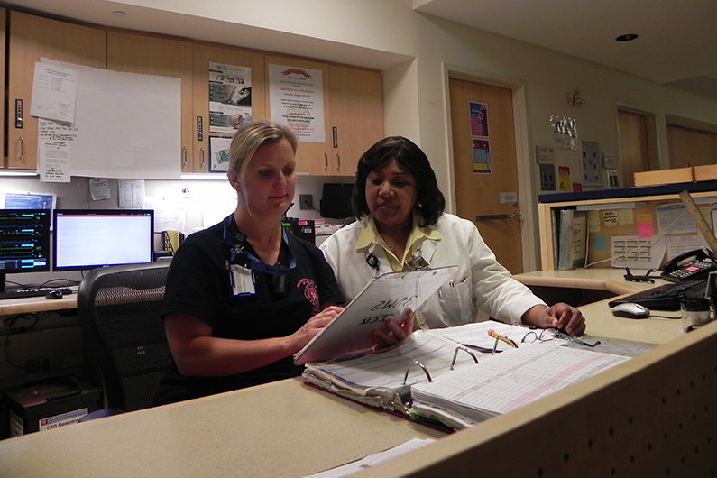 Administrative coordinator, Carole Henry, talks with charge nurse Danelle Gori on the intensive care unit during the night shift at the NIH Clinical Center Oct. 8.
