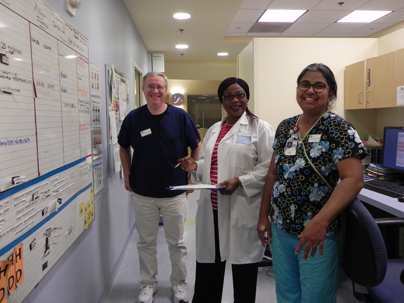Donna Owolabi, (middle in white lab coat) an administrative coordinator with the Nursing Department, discusses staffing with night shift staff during the evening shift at the NIH Clinical Center on Oct. 7