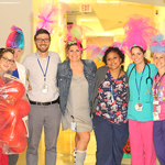 Seven members of the pediatric unit dress as Troll dolls. One dresses as a bag of red blood cells