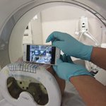 A cell phone held in front of a needle in a CT scanner