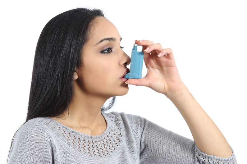 A woman using an asthma inhaler