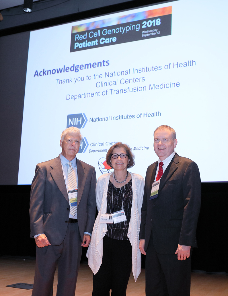 Dr. Gregory A. Denomme, Dr. Willy A. Flegel and Sue Johnson Stand in front of a screen with acknowledgements to say thank you to the NIH Department of Transfusion Medicine