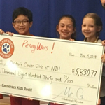 Four students and a teacher hold an oversized check to benefits patients at the NIH Clinical Center