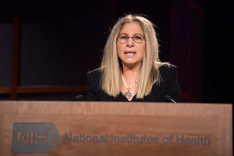 Barbra Streisand at a podium with NIH written on it
