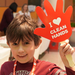 Young boy holds up a sign that says I love clean hands