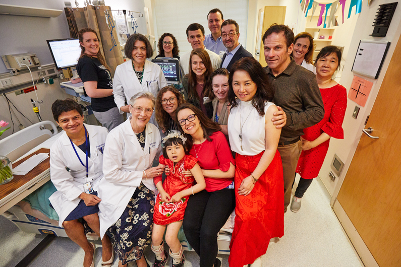 Pediatric patient surrounded by 15 adults who are a part of her care