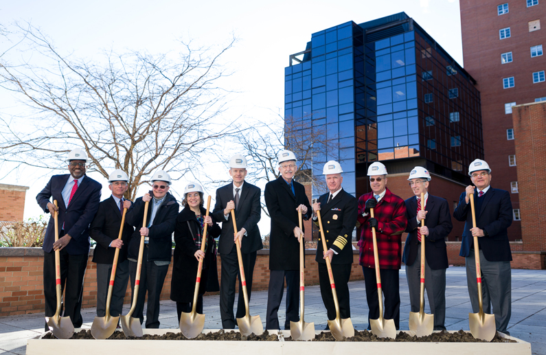 Men and Women holding shovels at the site of a new facility